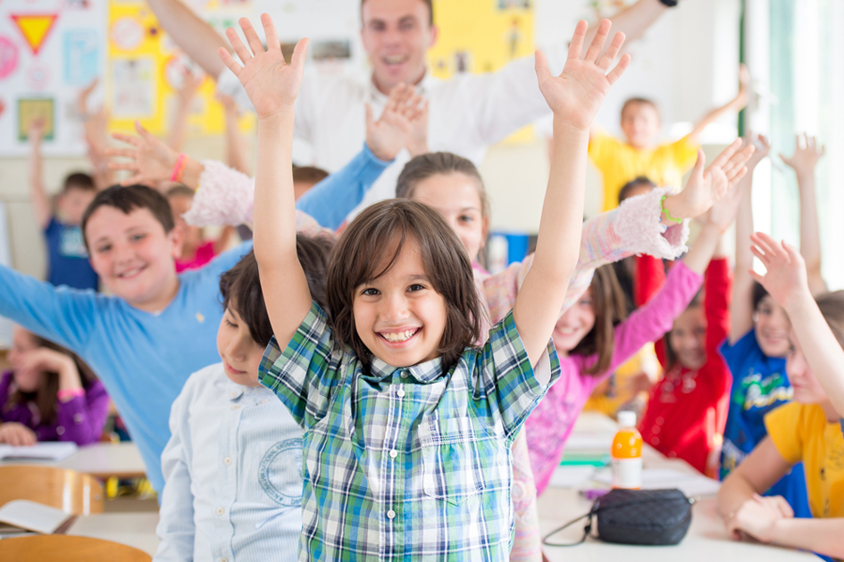 Young people waving hands in a classroom environment