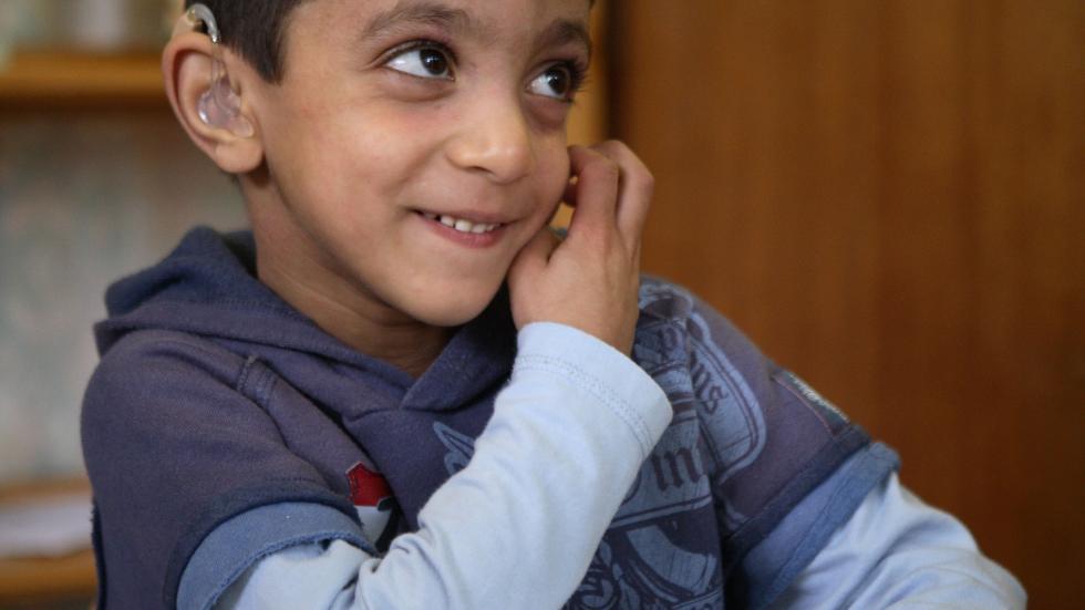 young student with hearing aid sitting at a desk