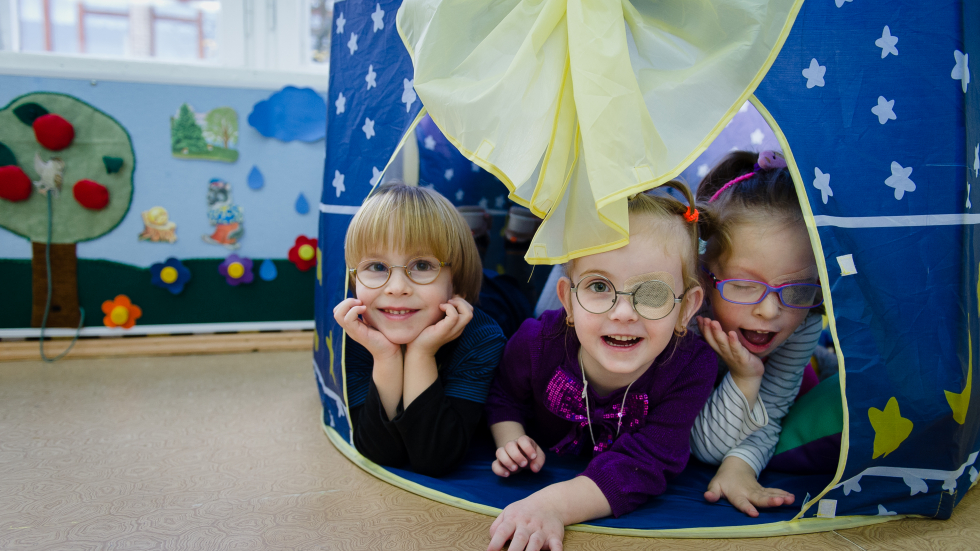 Three children play in a tent