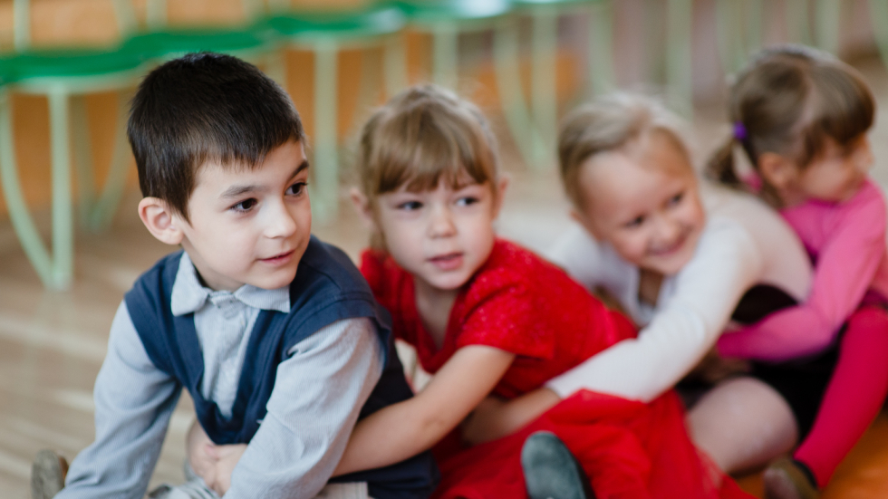 Belarusian pre-school children learning through drama at kindergarten. The photo was taken during a field visit to Vitebsk Oblast to document best practices in pre-school education in Belarus. Four children sitting on the floor with their arms linked around each other