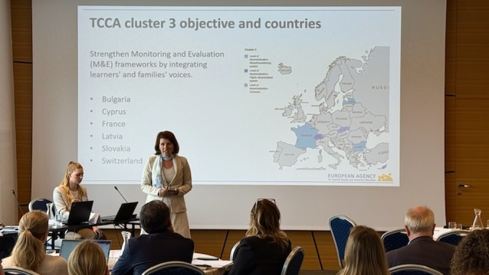 Katarína Reinoldová, National Co-ordinator for Slovakia, presenting the TCCA cluster 3 activities. A person presenting at the front of a room full of audience members sitting on chairs. The screen behind the speaker says 'TCCA cluster 3 objective and countries'