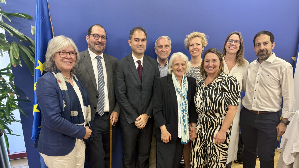 Some of the speakers at the meeting in Spain. A group of nine people standing in front of a bright blue wall.