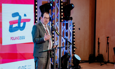 João Costa speaking on stage in front of a sign saying Poland 25