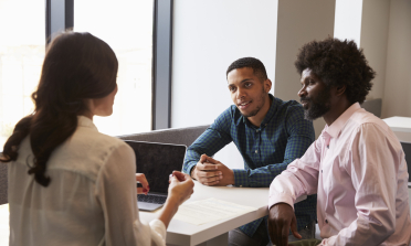 Three adults in discussion around a table