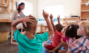 Children in a classroom with their hands in the air