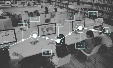 Children in a classroom, sitting in front of rows of computers. Overlaid on the image is a line graph, showing a range of percentages.