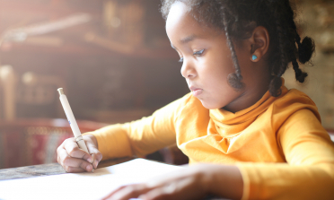 young girl writing at a table