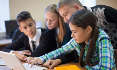 Children working at a computer with their teacher