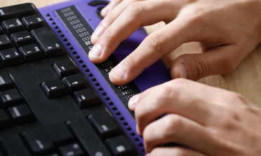 Hands hovering over a Braille keyboard