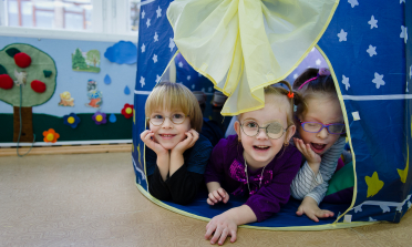 Three children play in a tent