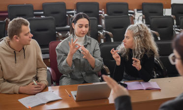 Three young people use sign language to present information to their teacher