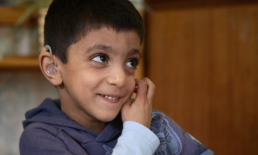 young student with hearing aid sitting at a desk