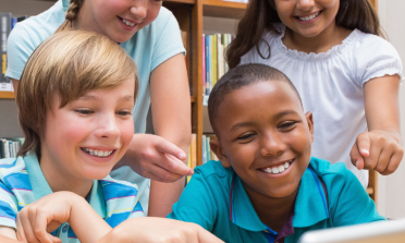 group of diverse children looking at a computer screen
