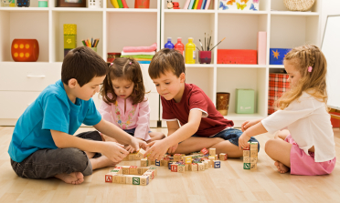 Four children playing with wooden building blocks