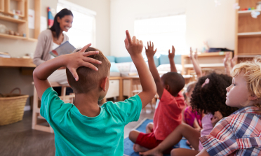 Children with their hands up in the classroom