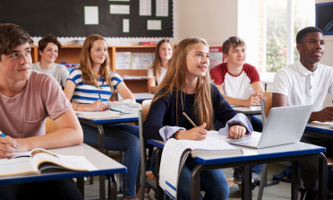 Teenagers sit at their desks in a classroom