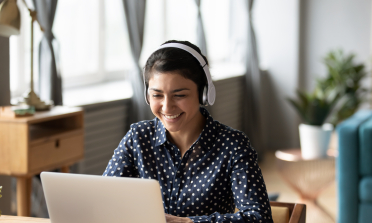 Person wearing headphones and smiling at a computer screen