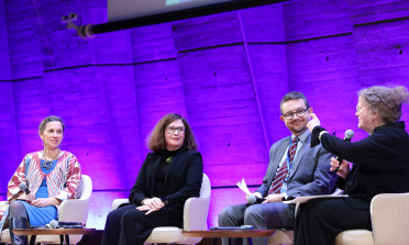 Amanda Watkins speaking on stage, alongside three other panelists © UNESCO/Marie ETCHEGOYEN