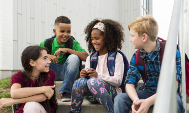 A group of children sit on some steps, smiling