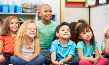 A group of children sitting on the floor and smiling