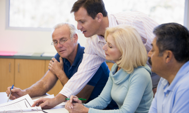 Four people discuss some paperwork