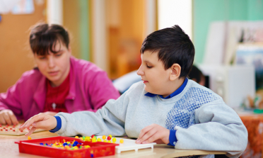 A boy putting coloured pegs in a board