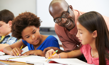 A child shows her school work to her teacher and a friend