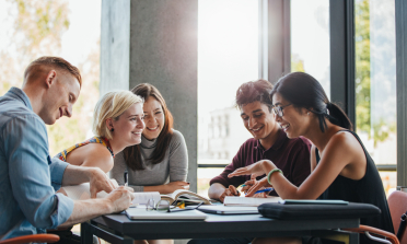 A group of students talking around a table full of books