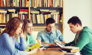 four young people reading at a table