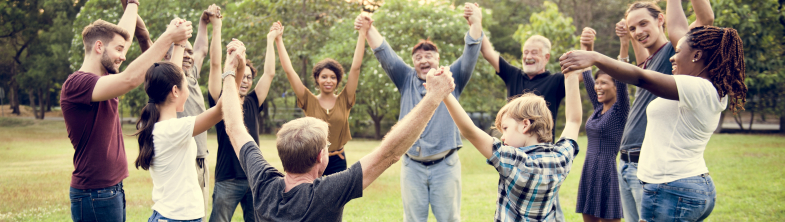 A group of people of different ages stand in a circle holding hands