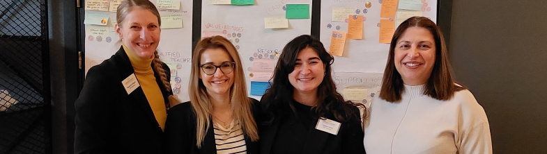 Four members of the project team stand in front of a display board