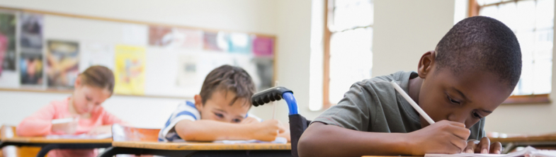 three children sit writing at their desks