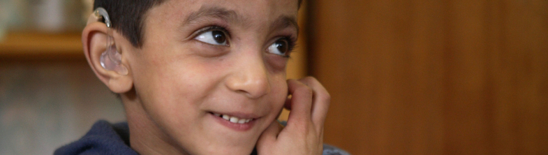 young student with hearing aid sitting at a desk