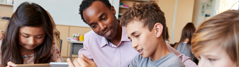 A child shows a teacher his work on a tablet