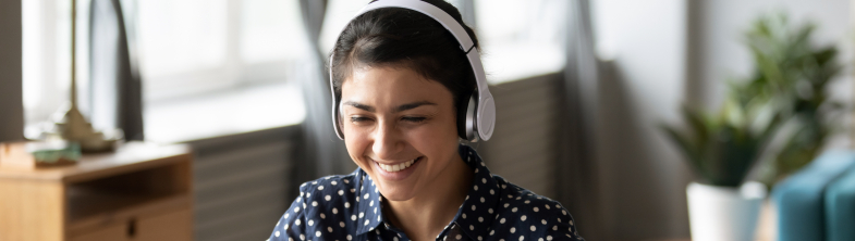 Person wearing headphones and smiling at a computer screen