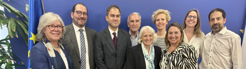 A group of nine people standing in front of a bright blue wall.