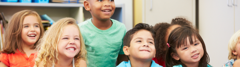 A group of children sitting on the floor and smiling