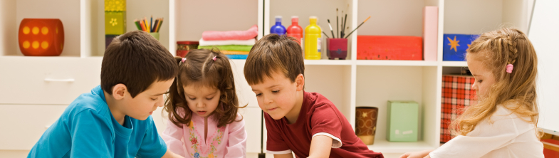Four children sit on the floor playing with building blocks