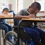 three children sit writing at their desks