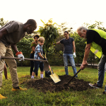 A group of people of different ages planting a tree