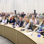 Participants in the conference sitting at desks in rows in a conference room