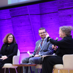 Amanda Watkins speaking on stage, alongside three other panelists © UNESCO/Marie ETCHEGOYEN
