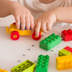 A child's hands, playing with colourful building blocks
