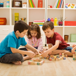 Four children sit on the floor playing with building blocks