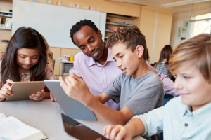 A child shows a teacher his work on a tablet