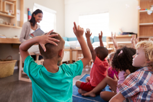 Children with their hands up in the classroom