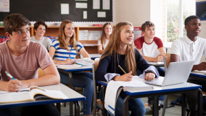 Teenagers sit at their desks in a classroom
