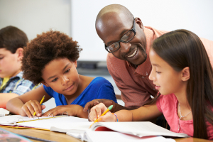 A child shows her school work to her teacher and a friend